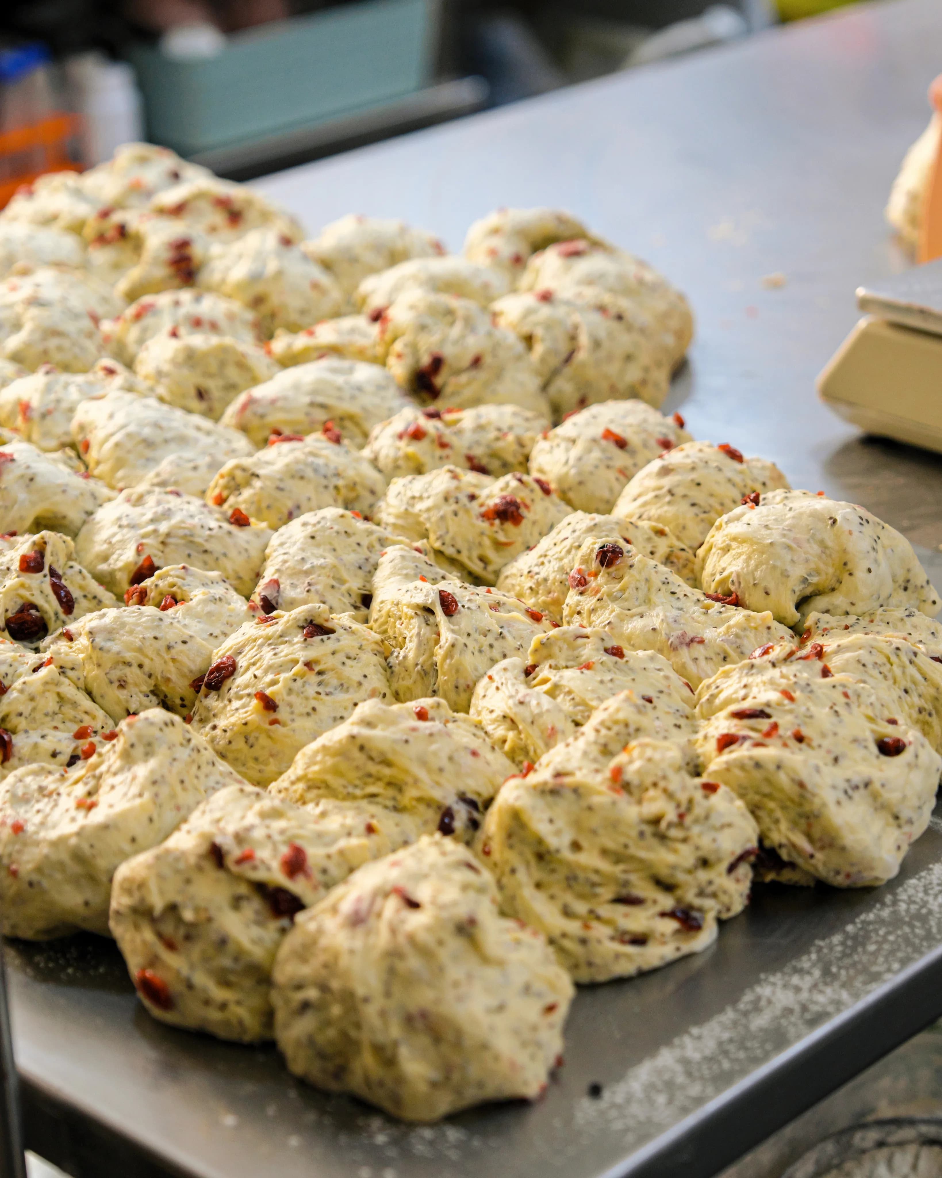 A tray of freshly shaped dough studded with dried fruit