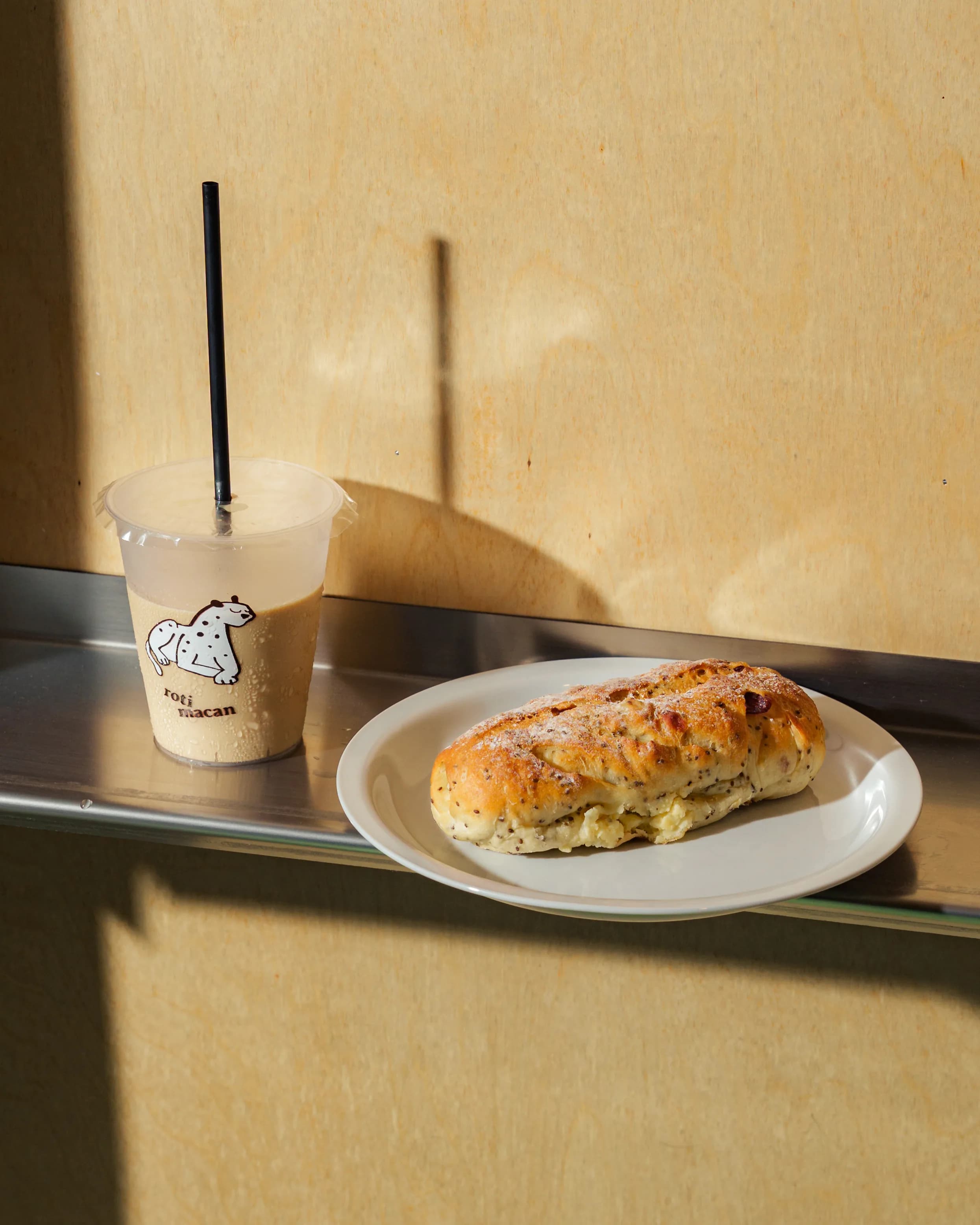 An iced coffee and a pastry on a tray by the shop window