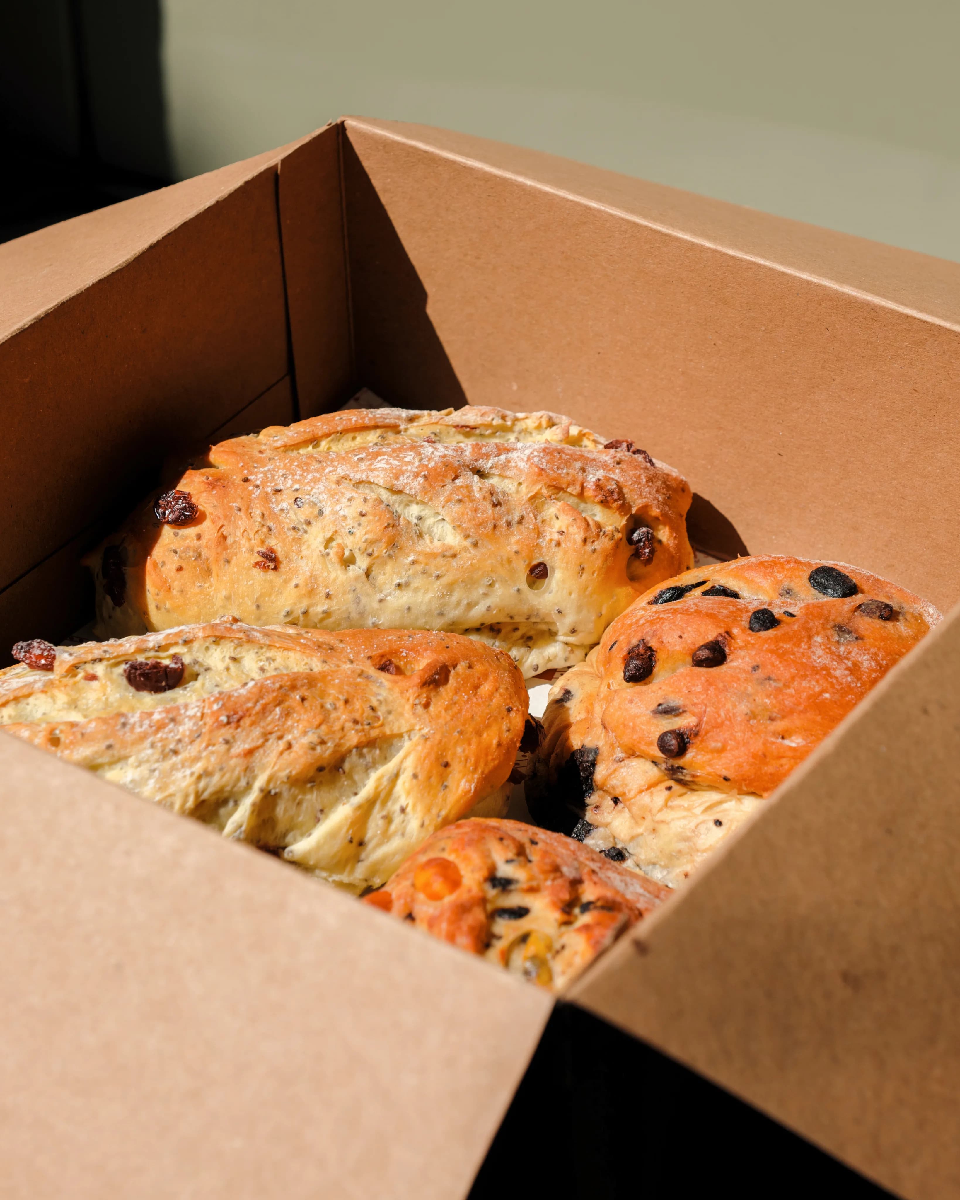 A box of finished loaves, chocolate and raisin and cheese side by side