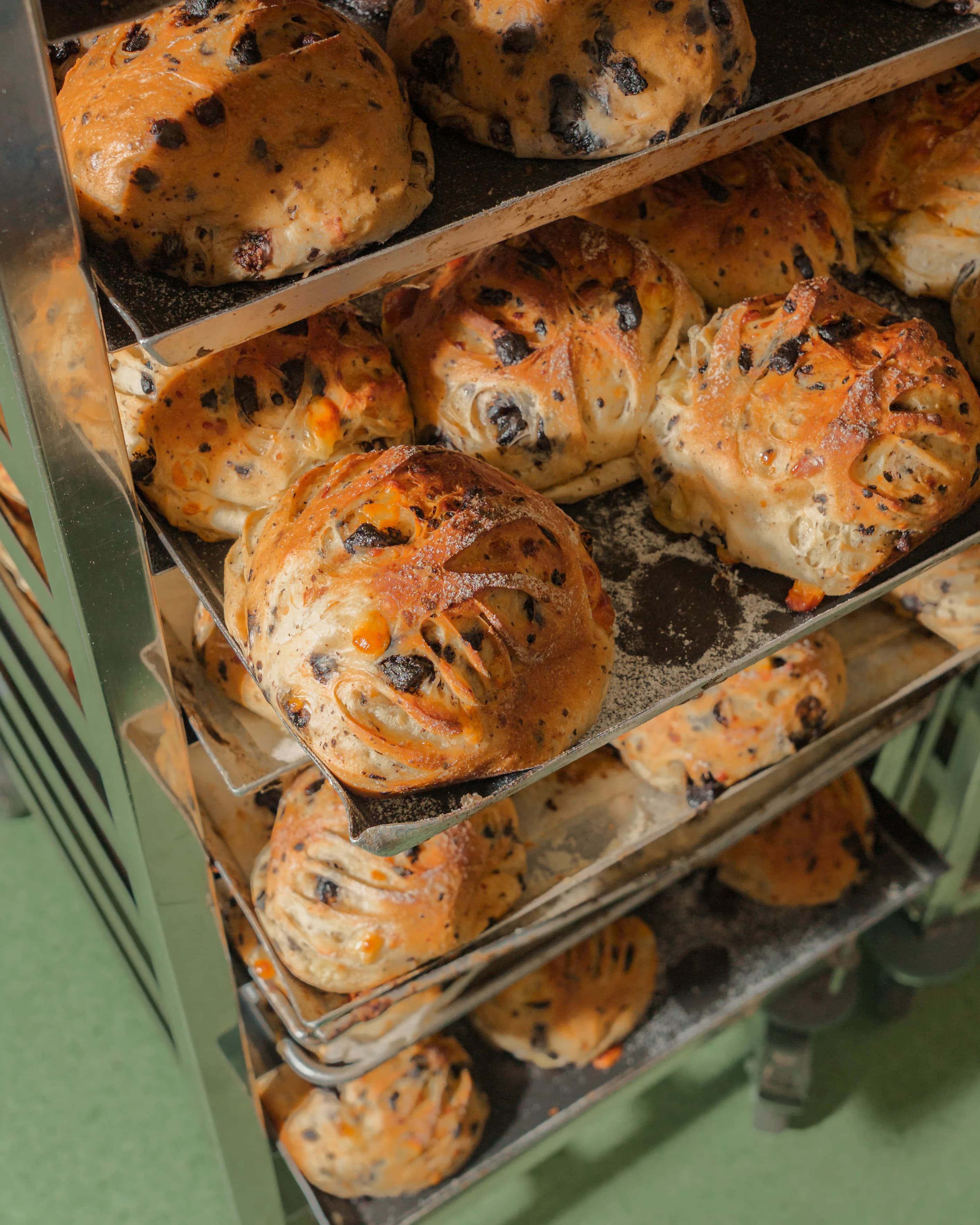 Trays of just-baked chocolate and cheese loaves stacked on a cooling rack